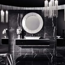 Baño negro con detalles blancos, paredes y piso de mármol, gran espejo central circular con marco de mármol blanco, lavabo blanco sobre modular en material negro brillante.