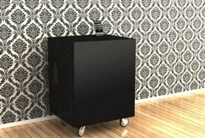 Modular pequeño con audio integrado en color negro, frente a pared empapelada con ornamentos y piso de madera clara